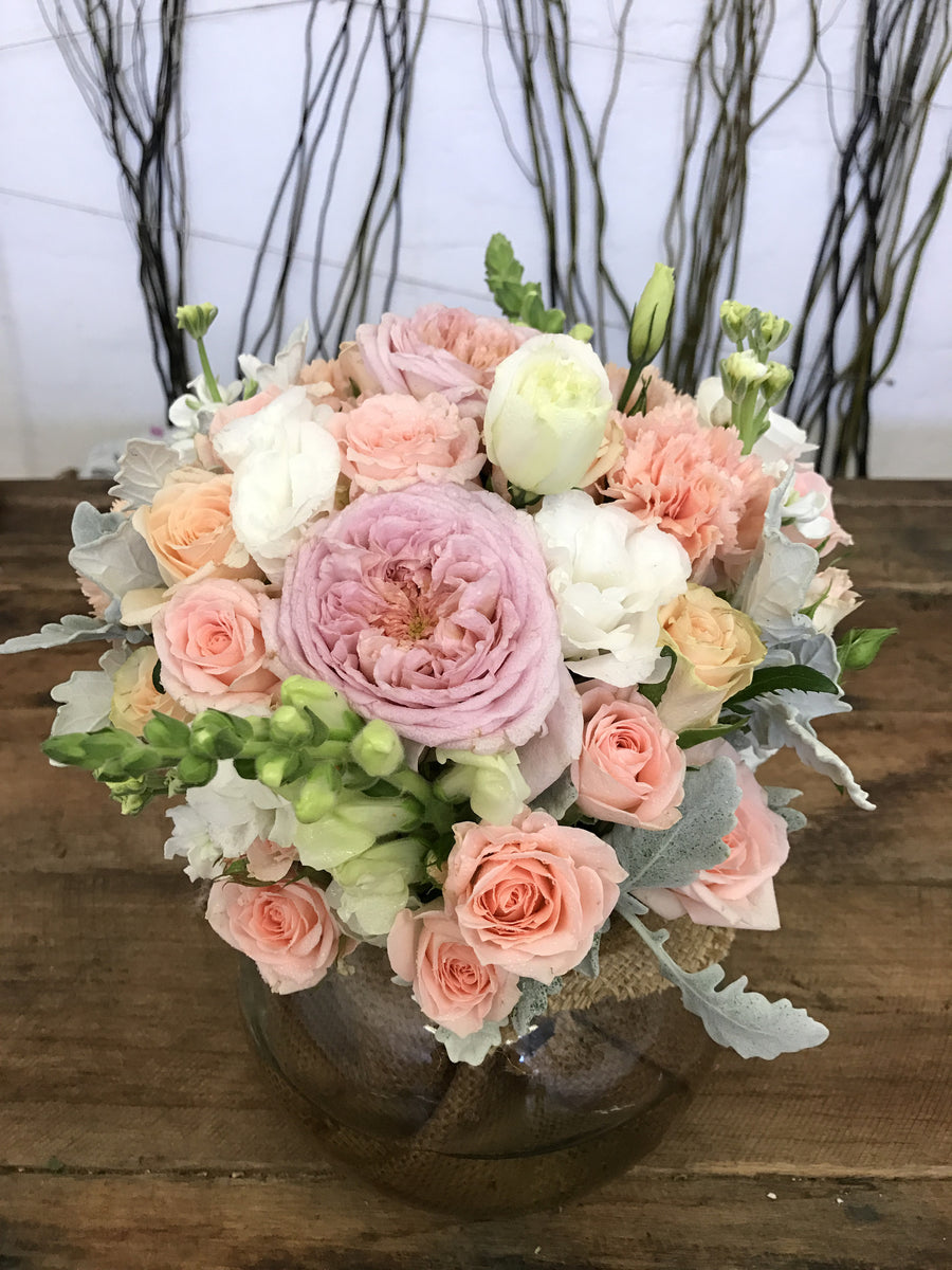 Pastel fresh flower arrangement in large fishbowl vase with roses and other seasonal fresh flowers